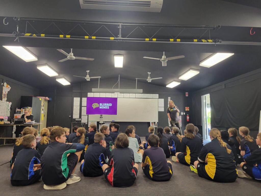 Students sitting on the floor watching a Blurred Minds presentation